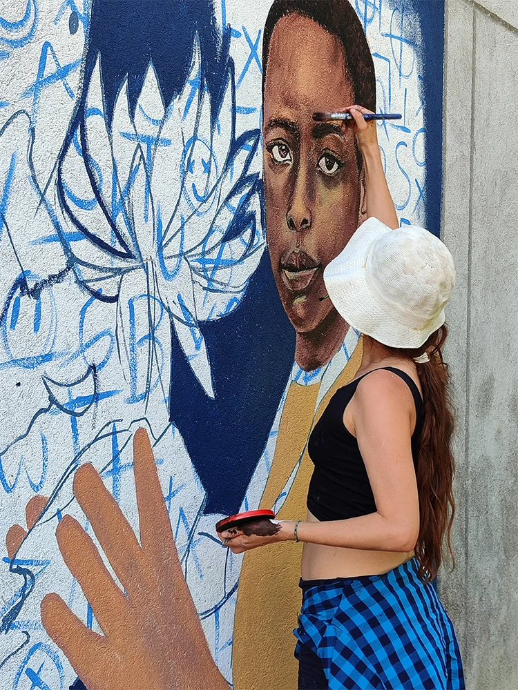 Natalia Martínez pintando un mural, detalle de mano con pincel, artista plástica Medellín