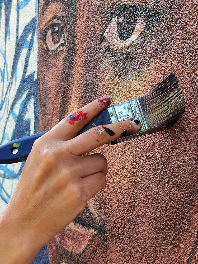 Natalia Martínez pintando un mural, detalle de mano con pincel, Chonta Colaboratorio de Artes